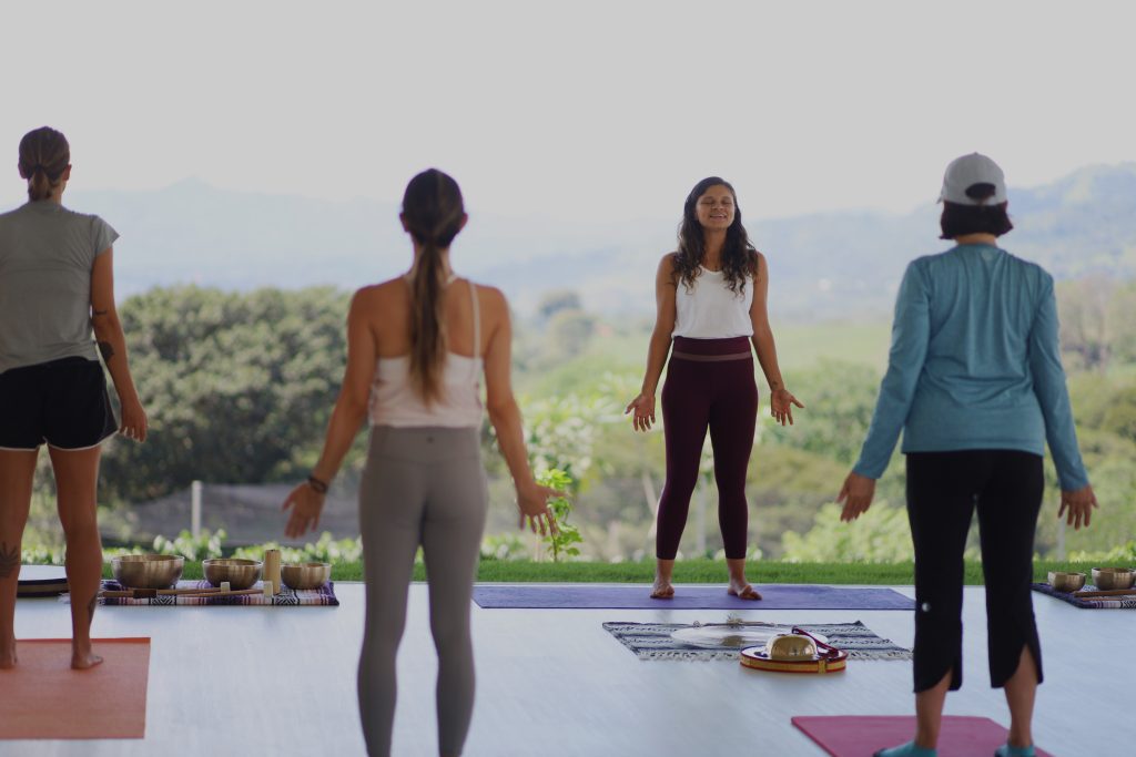 Cuatro personas haciendo yoga de pie en sus mats.
