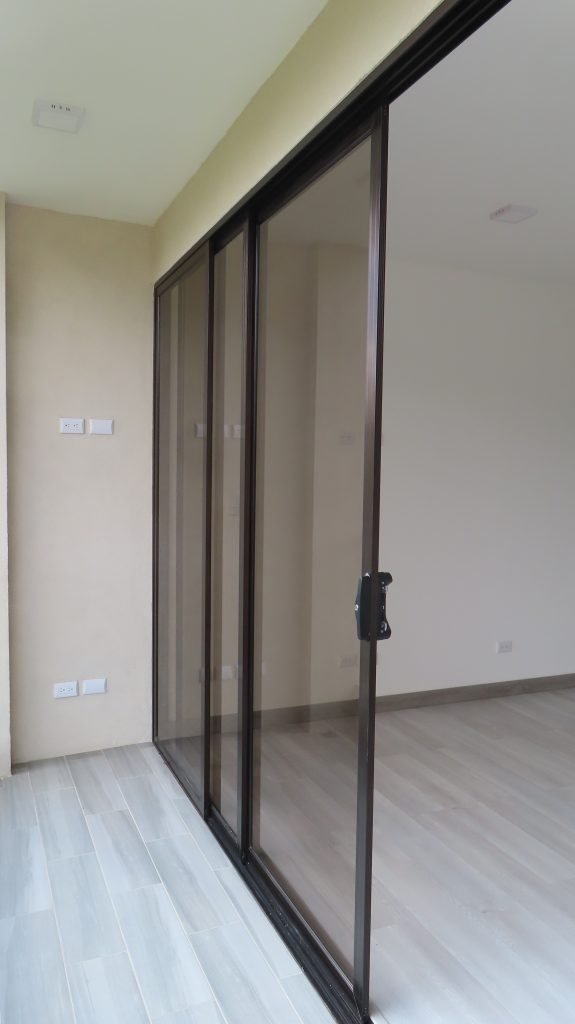 Las puertas se observan sobre el piso. El piso es gris. Las puertas estan corridas un poco para abrirse. Se ve el detalle del vidrio.